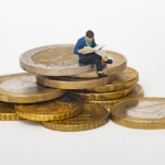 Wax figurine sitting on a pile of coins