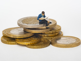 Wax figurine sitting on a pile of coins