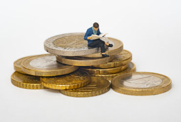 Wax figurine sitting on a pile of coins